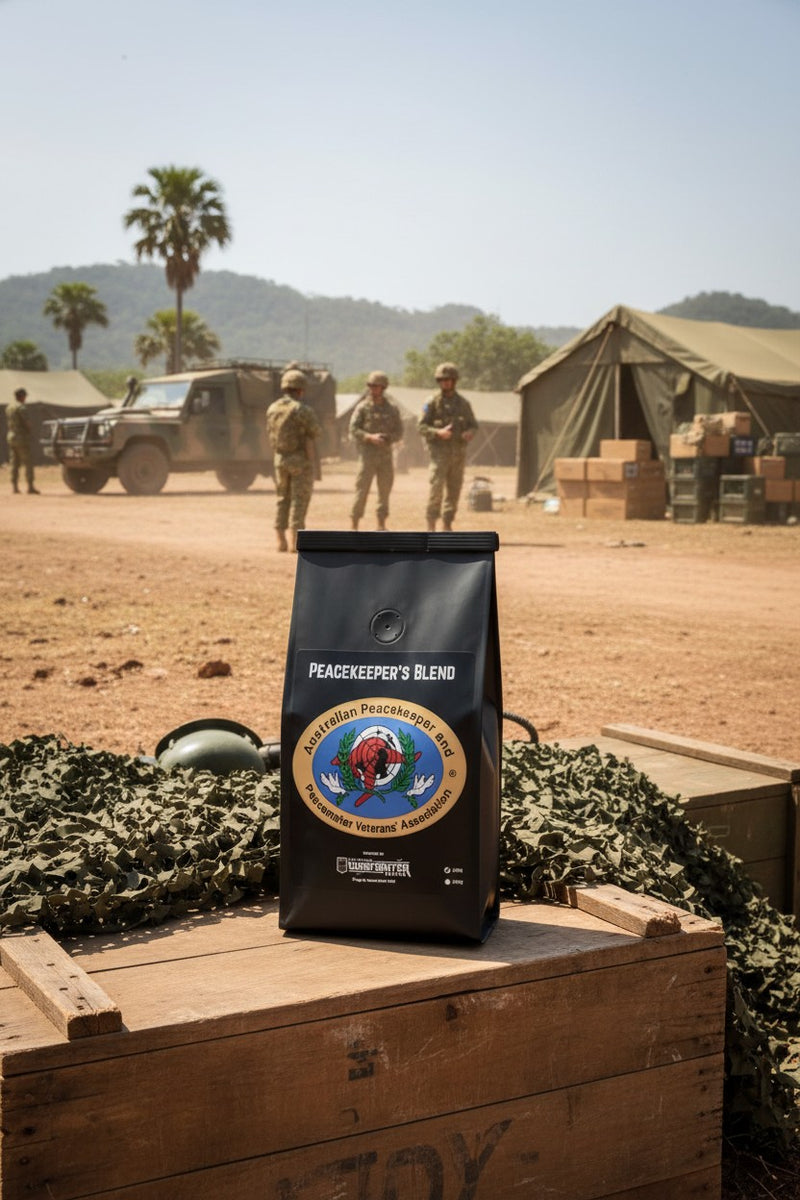 Coffee bag labeled 'Peacekeeper's Blend' on a wooden crate with military scene in the background